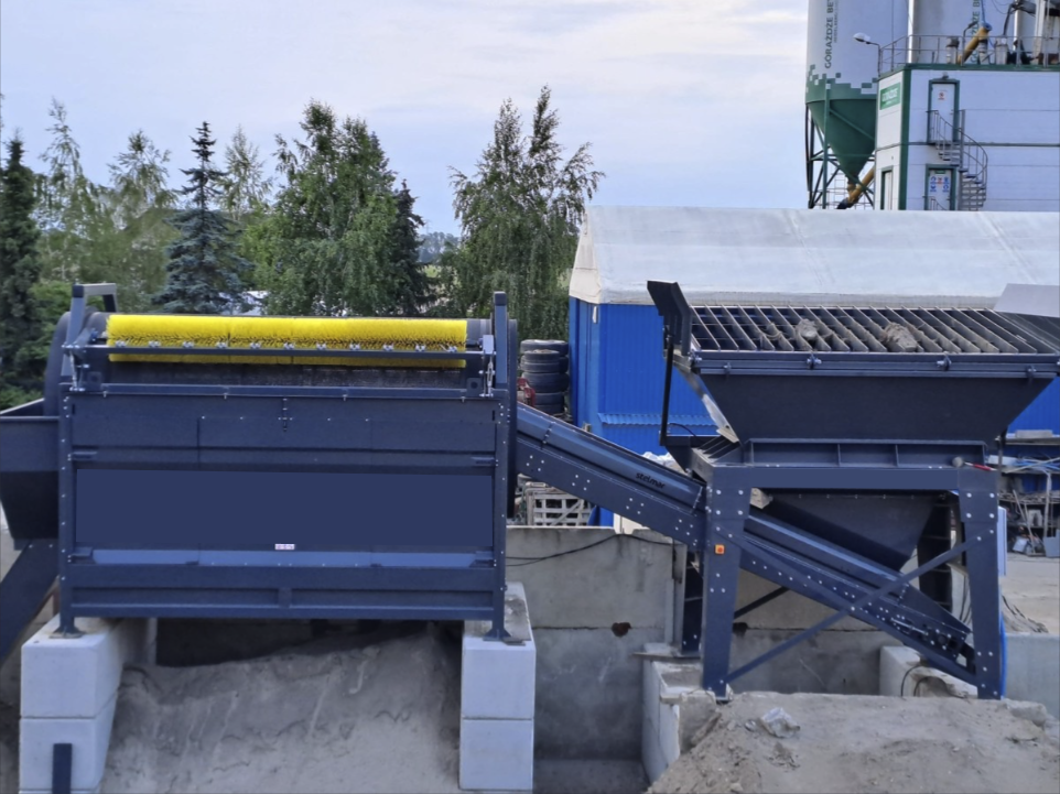 Trommel Ø 180 cm en poste fixe – DMB Machine Trommel Ø 180 cm DMB Machine en poste fixe sur plateforme de granulats, brosse jaune de nettoyage du tambour et convoyeur d'évacuation incliné