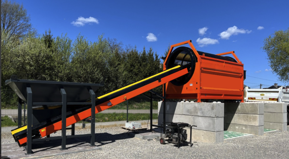 Trommel Ø 180 cm DMB Machine en installation sur site Trommel Ø 180 cm DMB Machine en poste fixe sur site : tambour rotatif orange et convoyeur d'évacuation de la matière criblée