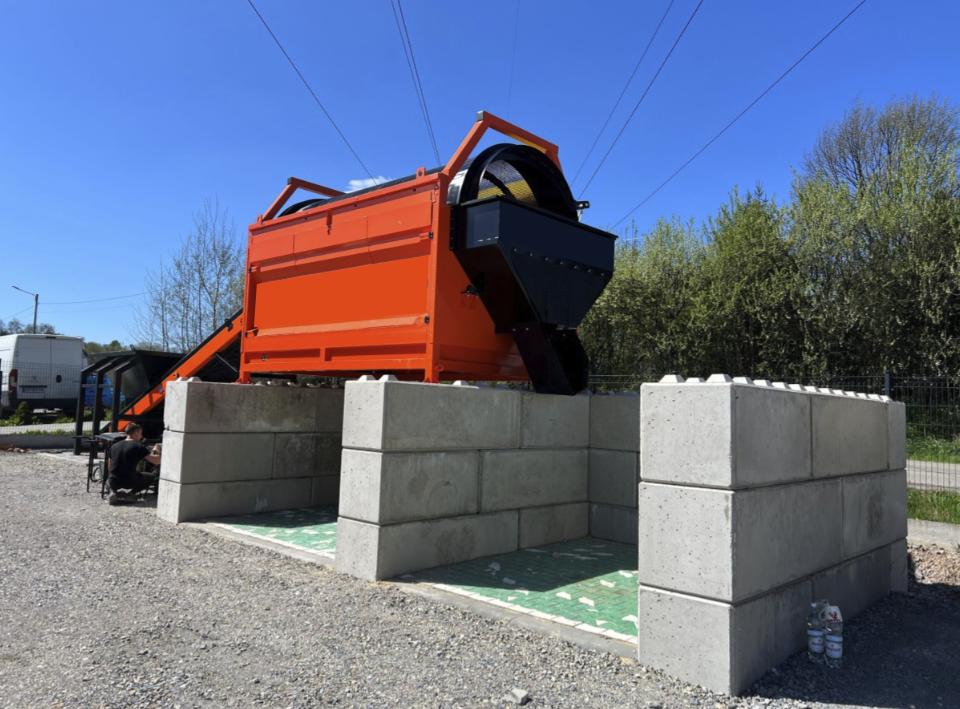 Trommel Ø 180 cm en poste fixe sur site – DMB Machine Trommel Ø 180 cm DMB Machine installé en poste fixe sur site, tambour perforé et alvéoles béton recueillant les matériaux triés par granulométrie