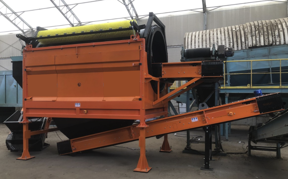 Trommel Ø 180 cm DMB Machine, vue d’ensemble en atelier Vue d'ensemble 3/4 d'un trommel Ø 180 cm orange DMB Machine en poste fixe, brosse de nettoyage du tambour et tapis d'évacuation